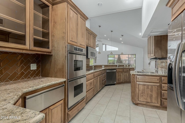 kitchen with light stone countertops, sink, decorative light fixtures, and appliances with stainless steel finishes