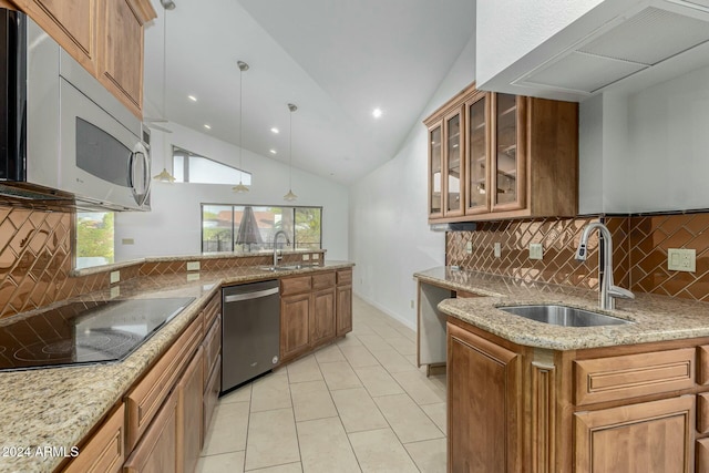 kitchen featuring pendant lighting, sink, vaulted ceiling, light stone counters, and stainless steel appliances