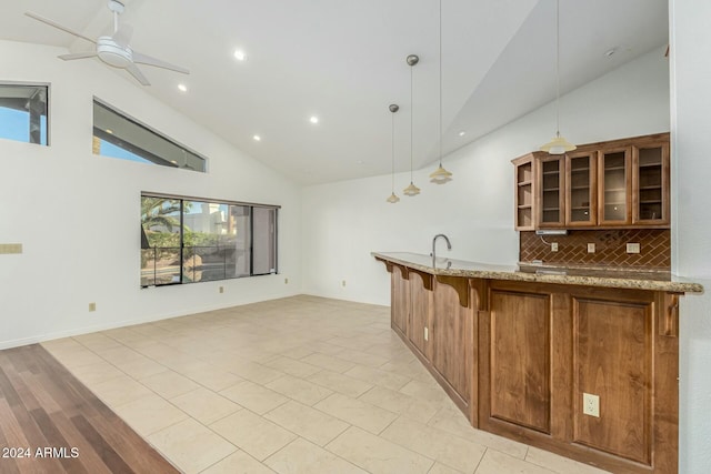 kitchen featuring tasteful backsplash, a wealth of natural light, light stone counters, and decorative light fixtures