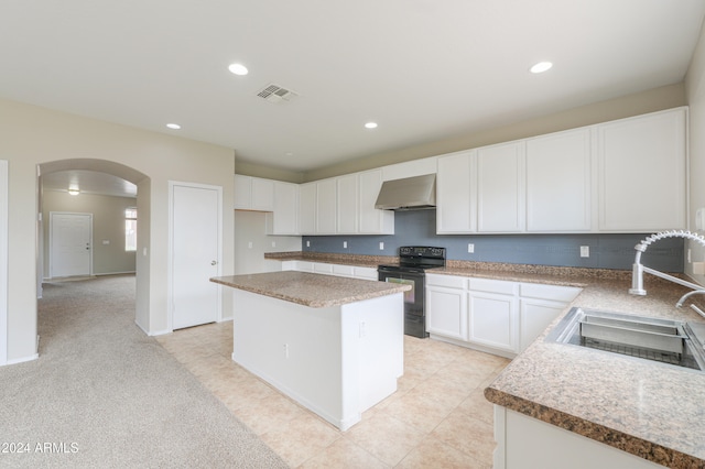 kitchen featuring wall chimney range hood, sink, a kitchen island, white cabinetry, and black / electric stove