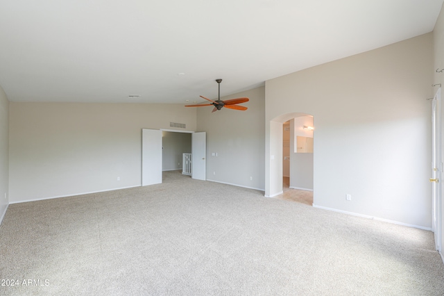 spare room featuring light carpet, lofted ceiling, and ceiling fan