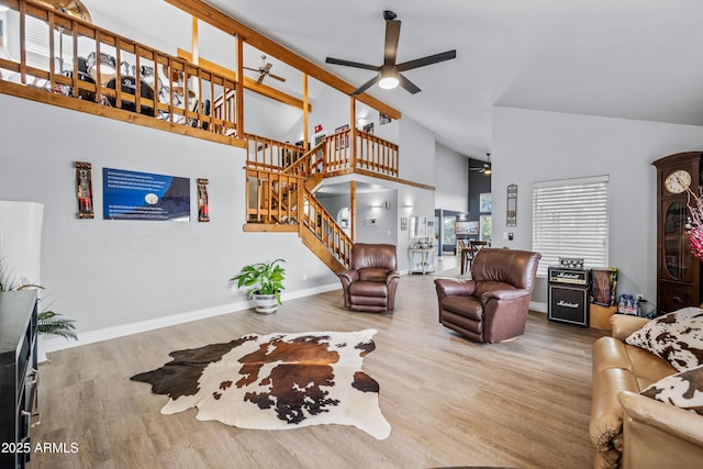 living room featuring high vaulted ceiling, ceiling fan, stairway, wood finished floors, and baseboards