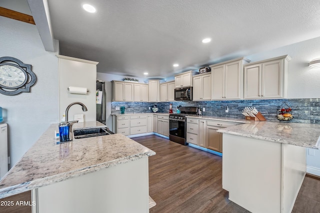 kitchen with tasteful backsplash, a peninsula, a sink, and appliances with stainless steel finishes