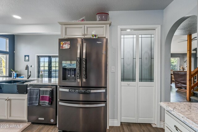 kitchen featuring arched walkways, dark wood-style flooring, dishwashing machine, and stainless steel refrigerator with ice dispenser