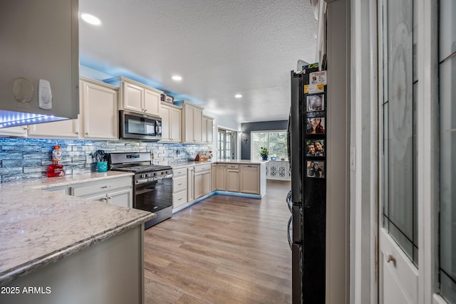 kitchen with recessed lighting, a peninsula, backsplash, and appliances with stainless steel finishes