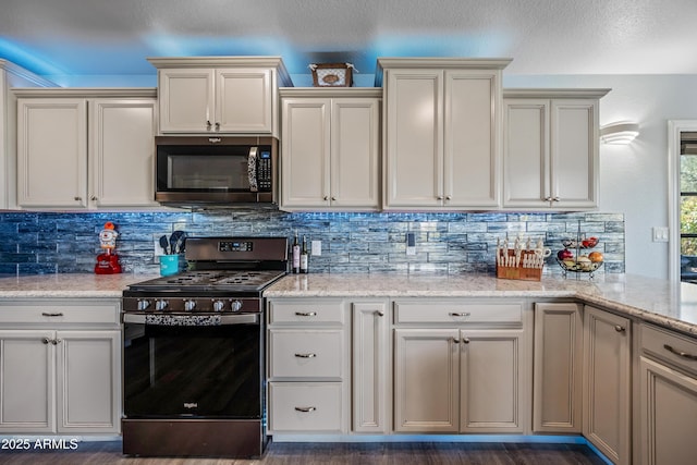 kitchen with tasteful backsplash, appliances with stainless steel finishes, light stone counters, and dark wood-type flooring