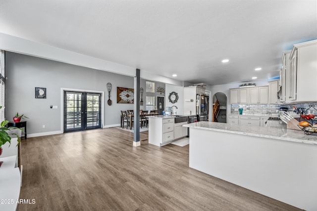 kitchen featuring recessed lighting, a peninsula, freestanding refrigerator, a sink, and wood finished floors