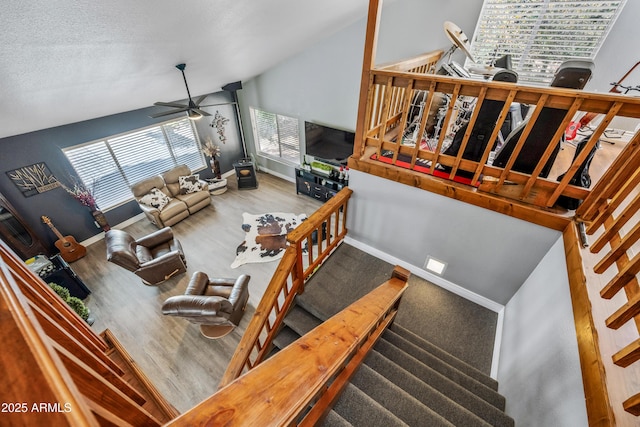 living area featuring wood finished floors, baseboards, a ceiling fan, and vaulted ceiling