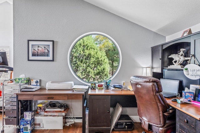 home office with wood finished floors, a textured wall, and vaulted ceiling