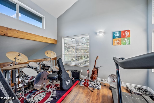 exercise room featuring high vaulted ceiling, baseboards, wood finished floors, and a healthy amount of sunlight