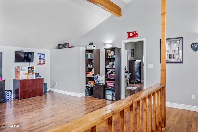 interior space featuring baseboards, vaulted ceiling with beams, and wood finished floors