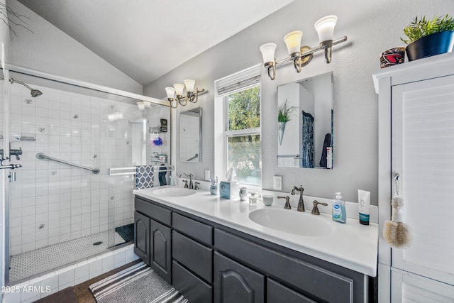 bathroom featuring a shower stall, double vanity, a sink, and lofted ceiling
