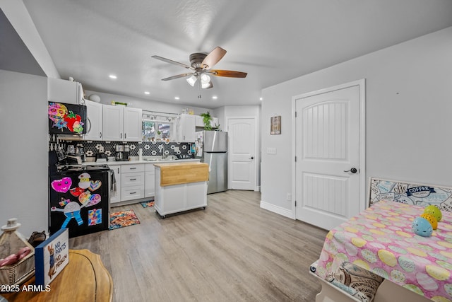 kitchen featuring ceiling fan, freestanding refrigerator, recessed lighting, light wood-style flooring, and decorative backsplash