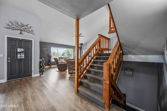 staircase with ceiling fan, baseboards, a textured ceiling, and wood finished floors