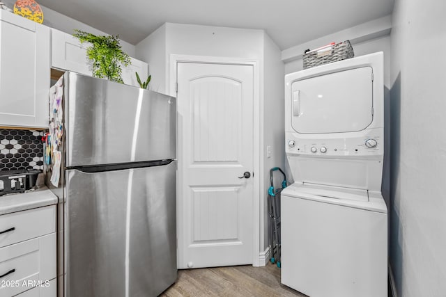 laundry room featuring stacked washer / dryer and light wood-type flooring