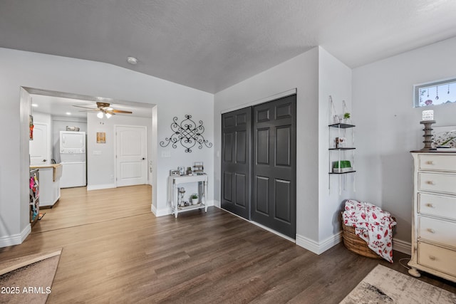 foyer entrance with baseboards, stacked washer / drying machine, a ceiling fan, and wood finished floors