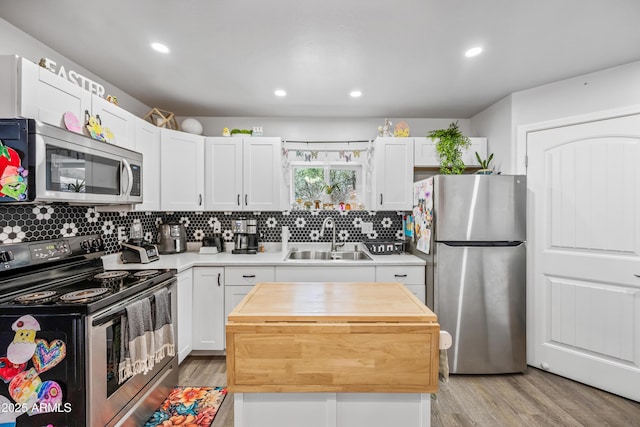 kitchen with tasteful backsplash, white cabinetry, appliances with stainless steel finishes, a sink, and wooden counters