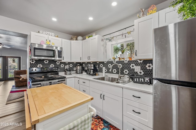 kitchen featuring white cabinets, recessed lighting, appliances with stainless steel finishes, a sink, and wooden counters