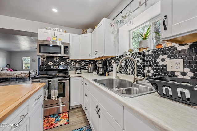 kitchen featuring butcher block countertops, a sink, white cabinetry, and stainless steel appliances