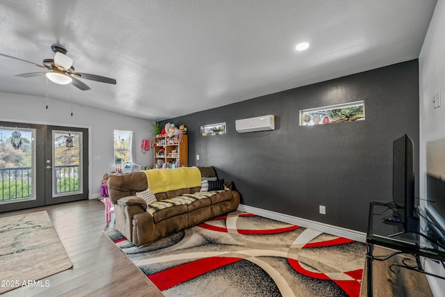 living area featuring ceiling fan, wood finished floors, french doors, a wall mounted air conditioner, and baseboards
