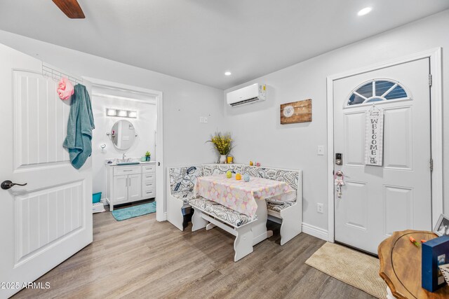 entrance foyer with light wood-type flooring, a wall mounted air conditioner, baseboards, and recessed lighting