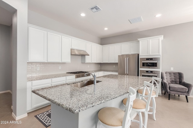 kitchen with extractor fan, appliances with stainless steel finishes, light stone countertops, sink, and white cabinets