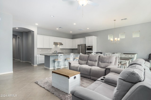 living room featuring light tile patterned flooring, ceiling fan with notable chandelier, and sink