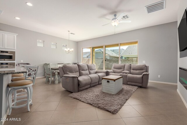 tiled living room featuring ceiling fan with notable chandelier