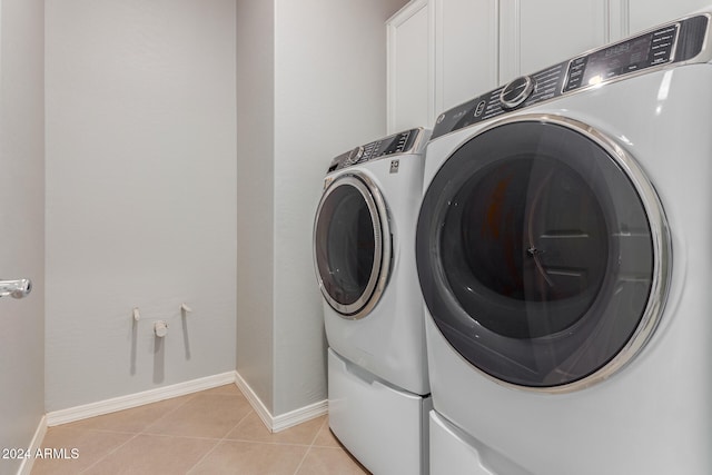 laundry area with cabinets, light tile patterned floors, and washer and dryer