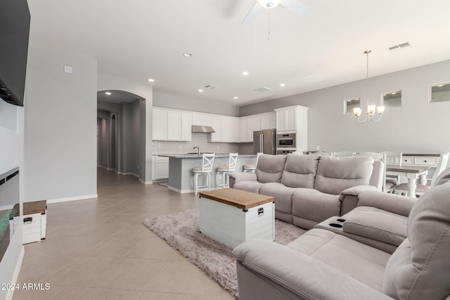 tiled living room featuring ceiling fan with notable chandelier and sink