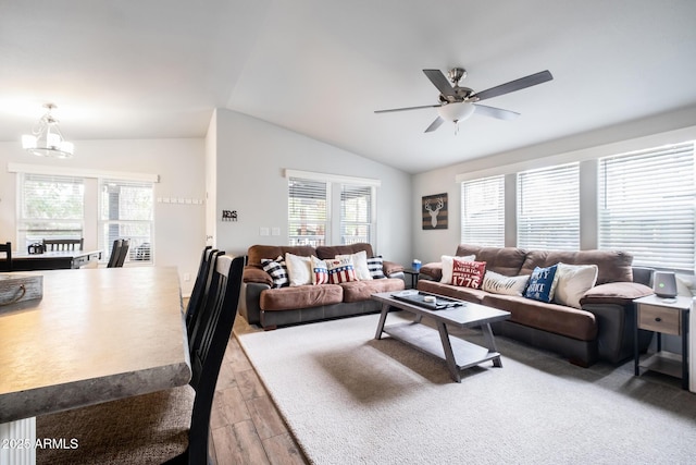 living room with plenty of natural light, lofted ceiling, ceiling fan with notable chandelier, and light wood finished floors