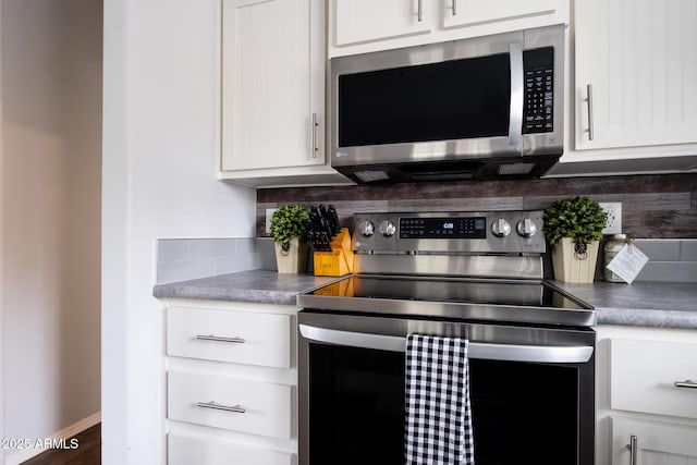 kitchen with decorative backsplash, appliances with stainless steel finishes, and white cabinetry