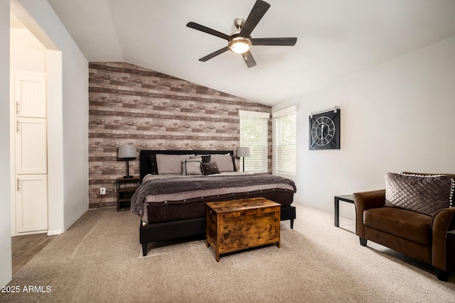 carpeted bedroom with an accent wall, lofted ceiling, wooden walls, and a ceiling fan