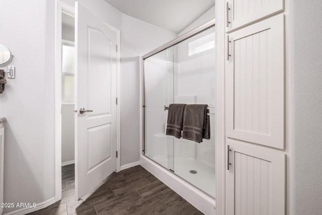 full bathroom featuring a shower stall, wood finished floors, and baseboards