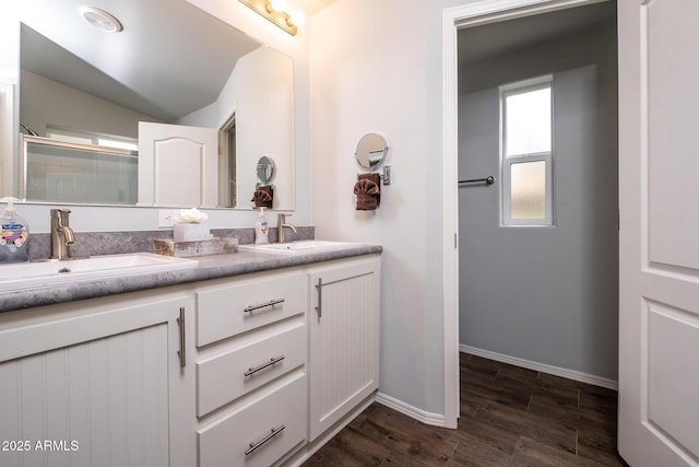 full bathroom with double vanity, wood finished floors, baseboards, and a sink