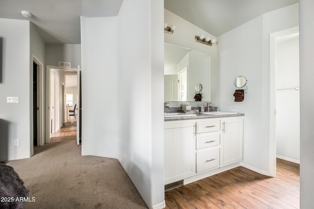 bathroom with double vanity, wood finished floors, visible vents, and a sink