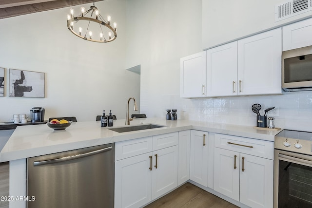 1021 S Almar Cir, Mesa, AZ 85204 - kitchen with stainless steel appliances, a sink, a peninsula, white cabinetry, and decorative backsplash