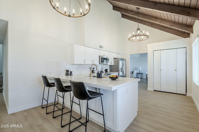 1021 S Almar Cir, Mesa, AZ 85204 - kitchen featuring appliances with stainless steel finishes, a chandelier, a peninsula, wooden ceiling with exposed beams, and light countertops