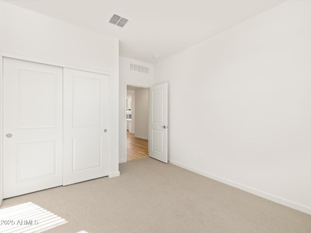 unfurnished bedroom with light colored carpet and a closet