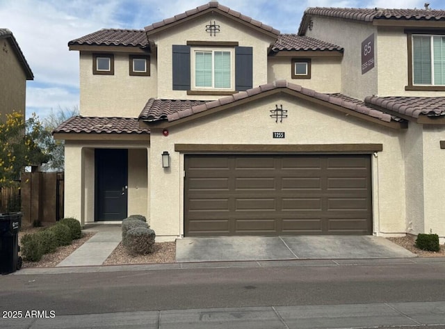 view of front of home with stucco siding, driveway, a tile roof, and a garage