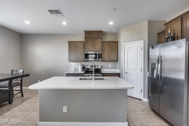 kitchen featuring visible vents, a center island with sink, appliances with stainless steel finishes, light countertops, and light tile patterned floors