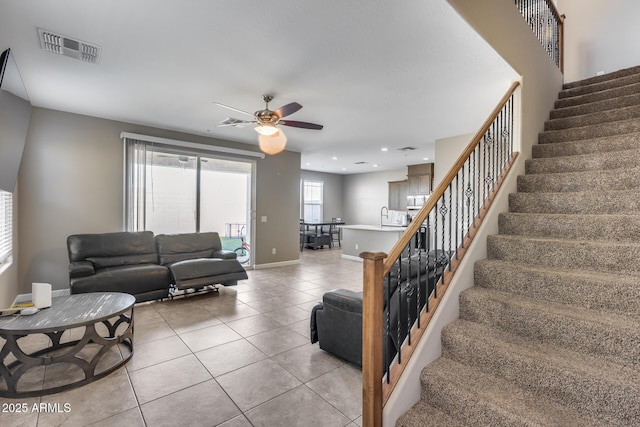 living room featuring visible vents, a ceiling fan, stairway, light tile patterned floors, and baseboards