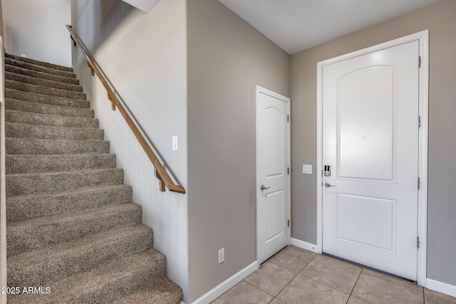 entryway featuring light tile patterned flooring, stairway, and baseboards