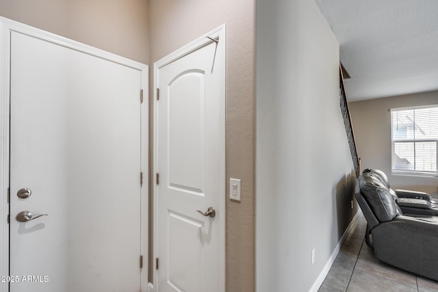 hallway featuring baseboards and light tile patterned flooring