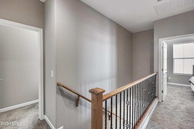 corridor featuring baseboards, an upstairs landing, visible vents, and carpet flooring