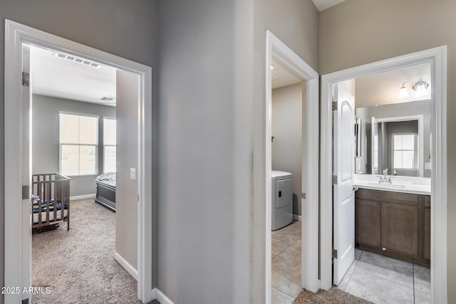 hallway with plenty of natural light, washer / clothes dryer, visible vents, and a sink