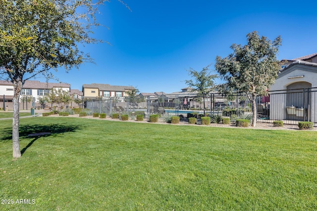 view of property's community with a pool, a yard, fence, and a residential view