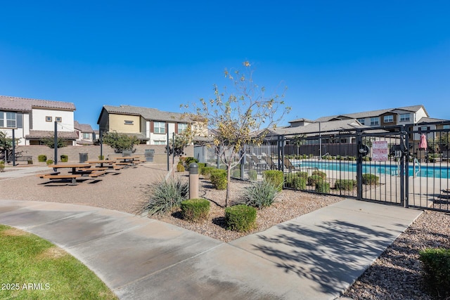 view of community featuring a swimming pool, a residential view, and fence