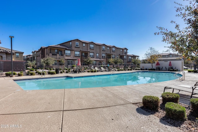 pool with a patio, fence, and a residential view