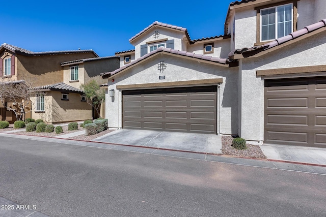 mediterranean / spanish house featuring a tiled roof, a garage, driveway, and stucco siding